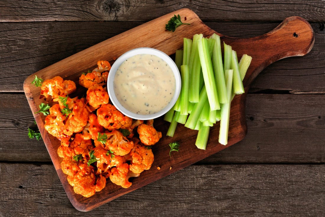 Vegan Diet (Guide for Beginners) 93 Cauliflower buffalo wings with celery and ranch dip. Top view on a wood paddle board. Healthy eating, plant based meat substitute concept.
